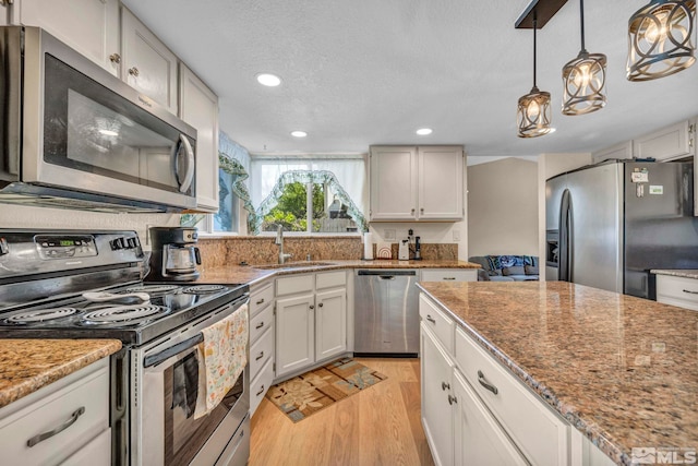 5245 Canyon View Dr, Sparks, NV 89436 - kitchen featuring stainless steel appliances, light wood finished floors, a sink, decorative light fixtures, and recessed lighting