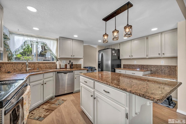5245 Canyon View Dr, Sparks, NV 89436 - kitchen with appliances with stainless steel finishes, light wood-style flooring, a sink, dark stone counters, and a center island
