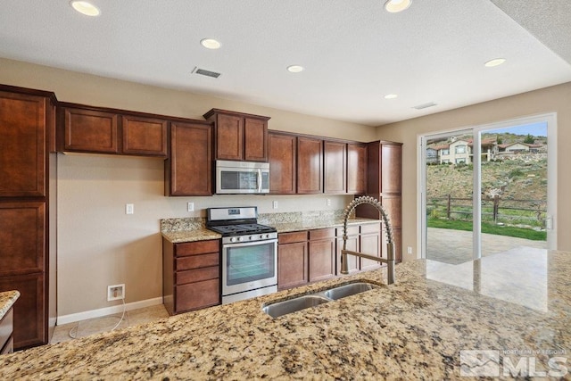 kitchen featuring appliances with stainless steel finishes, a sink, light stone counters, recessed lighting, and baseboards