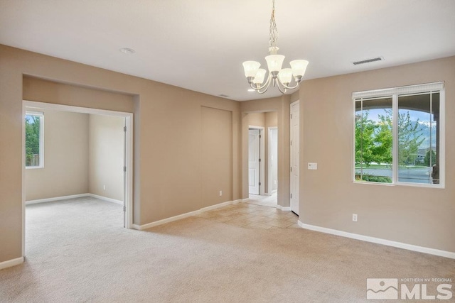 spare room with light colored carpet, a chandelier, plenty of natural light, and baseboards