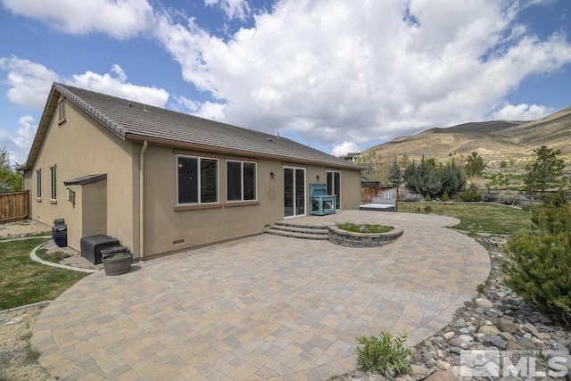 rear view of property featuring a patio, stucco siding, fence, a mountain view, and a tile roof