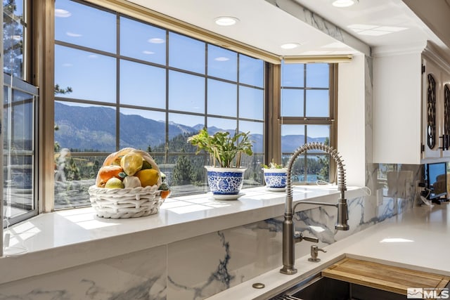 kitchen view of a mountain view, light countertops, a sink, and recessed lighting