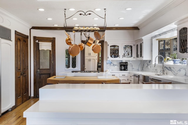 kitchen featuring ornamental molding, light wood-style floors, light countertops, white cabinetry, and backsplash
