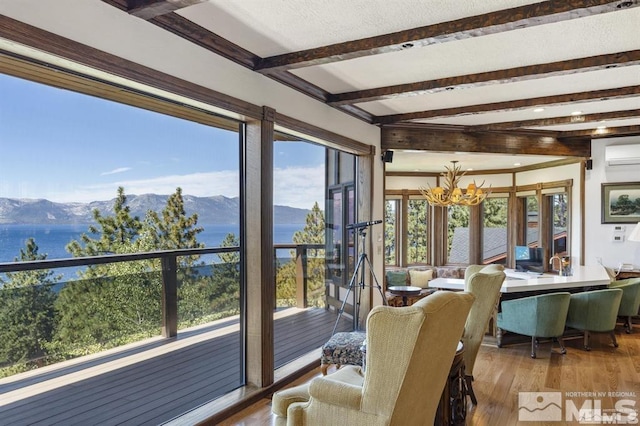 sunroom / solarium with a wall mounted air conditioner, beamed ceiling, a chandelier, and a water and mountain view