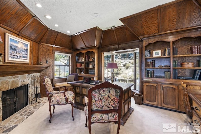office area featuring wood walls, a textured ceiling, light carpet, a fireplace, and recessed lighting