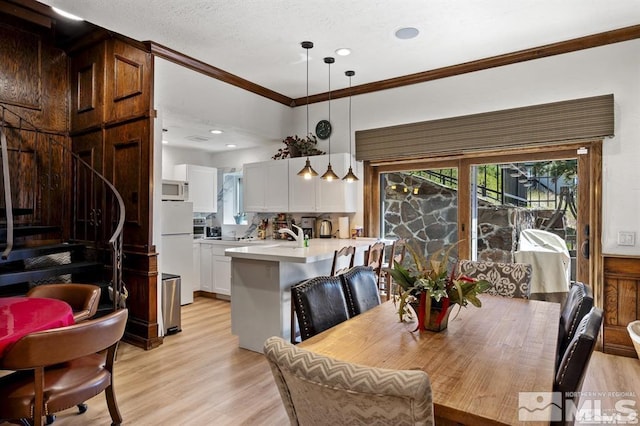 dining space with light wood-style flooring, ornamental molding, and recessed lighting