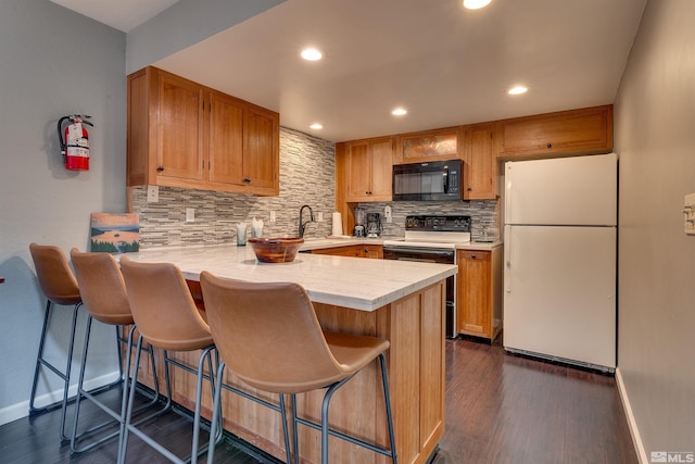 kitchen featuring freestanding refrigerator, black microwave, electric range, a peninsula, and tasteful backsplash