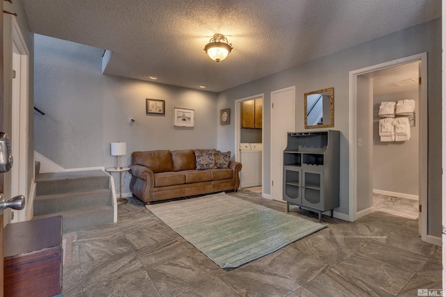 living room featuring stairway, washer / clothes dryer, marble finish floors, a textured ceiling, and baseboards