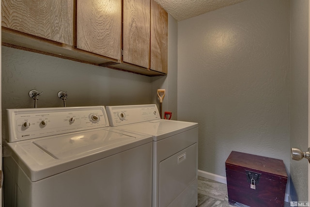 laundry room featuring independent washer and dryer, baseboards, cabinet space, a textured ceiling, and a textured wall