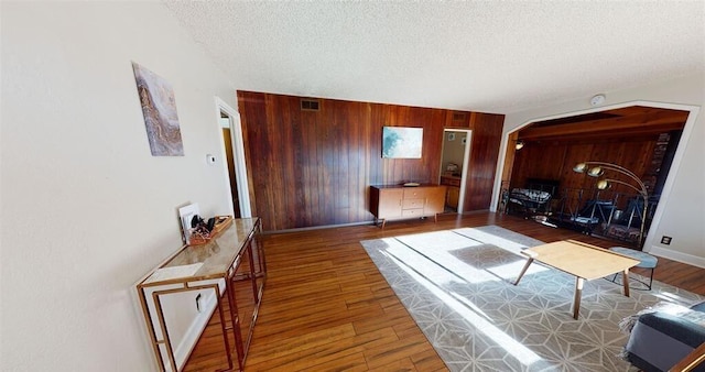 50 Bellevue Ave, Winnemucca, NV 89445 - living room featuring wooden walls, a textured ceiling, arched walkways, wood finished floors, and baseboards