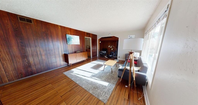 50 Bellevue Ave, Winnemucca, NV 89445 - living room with arched walkways, wooden walls, a textured ceiling, wood finished floors, and baseboards