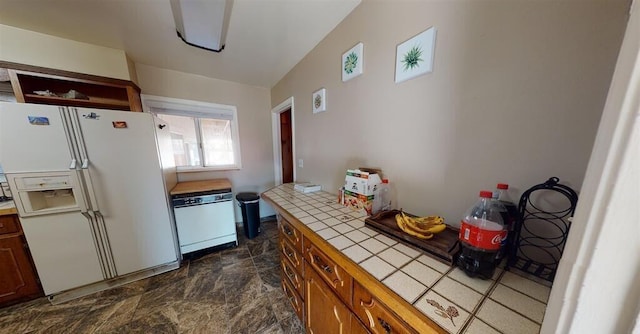 50 Bellevue Ave, Winnemucca, NV 89445 - kitchen featuring white appliances, tile counters, dark stone finish floors, and brown cabinetry