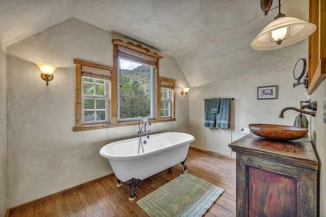 3150 Kings Canyon Rd, Carson City, NV 89703 - bathroom featuring vaulted ceiling, wood finished floors, vanity, a soaking tub, and baseboards