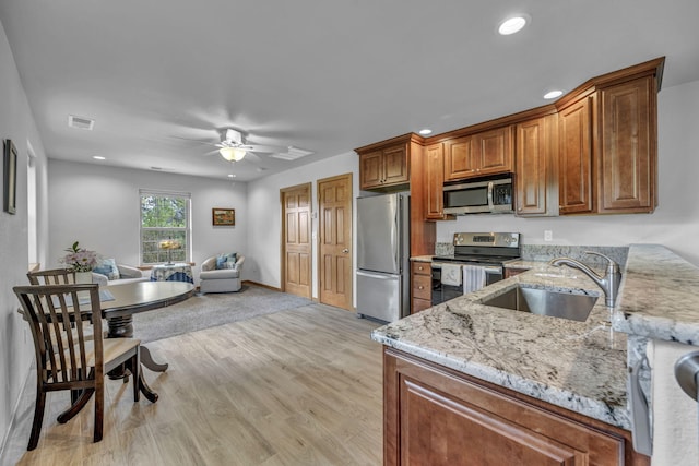 3150 Kings Canyon Rd, Carson City, NV 89703 - kitchen featuring appliances with stainless steel finishes, a sink, light stone countertops, ceiling fan, and brown cabinetry