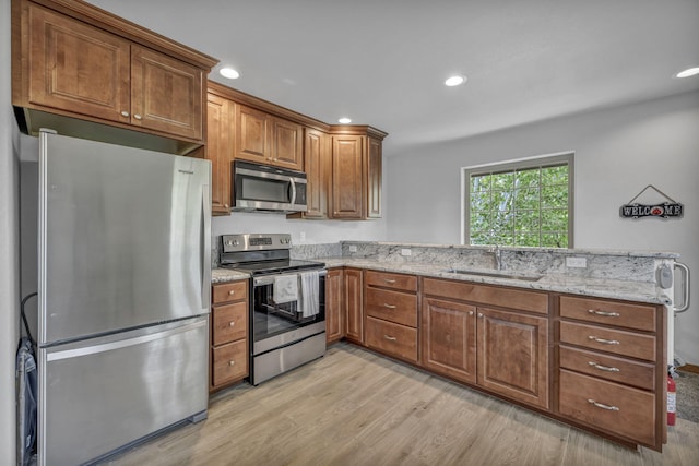 3150 Kings Canyon Rd, Carson City, NV 89703 - kitchen featuring appliances with stainless steel finishes, a sink, a peninsula, light wood-style flooring, and brown cabinetry