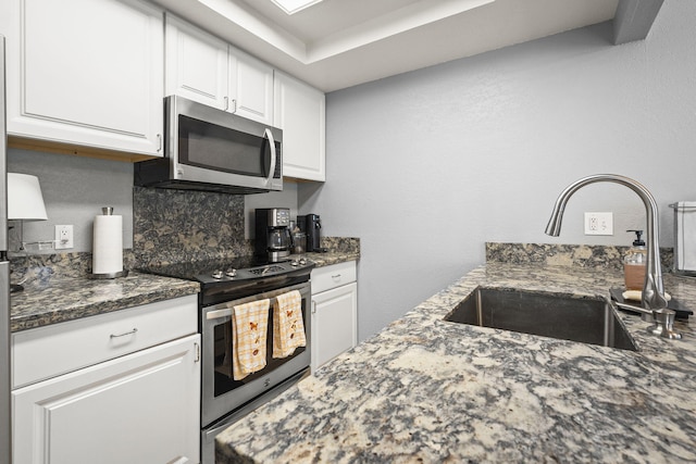 2107 G St, Sparks, NV 89431 - kitchen with appliances with stainless steel finishes, a sink, white cabinets, tasteful backsplash, and dark stone countertops