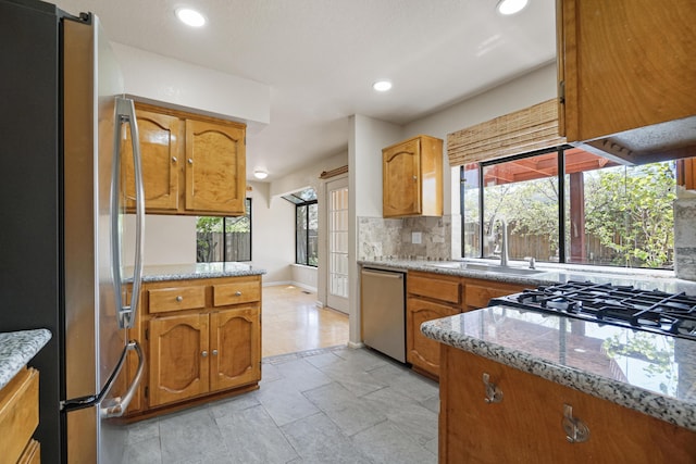1043 Shenandoah Dr, Carson City, NV 89702 - kitchen with stainless steel appliances, a sink, decorative backsplash, brown cabinets, and healthy amount of natural light