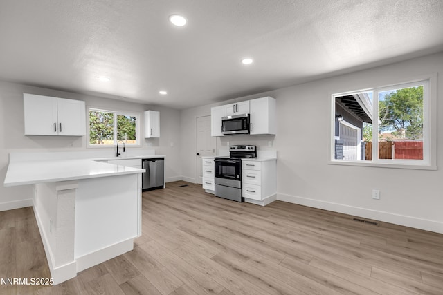 1717 Rio Tinto Dr, Sparks, NV 89434 - kitchen with appliances with stainless steel finishes, baseboards, white cabinets, a peninsula, and recessed lighting