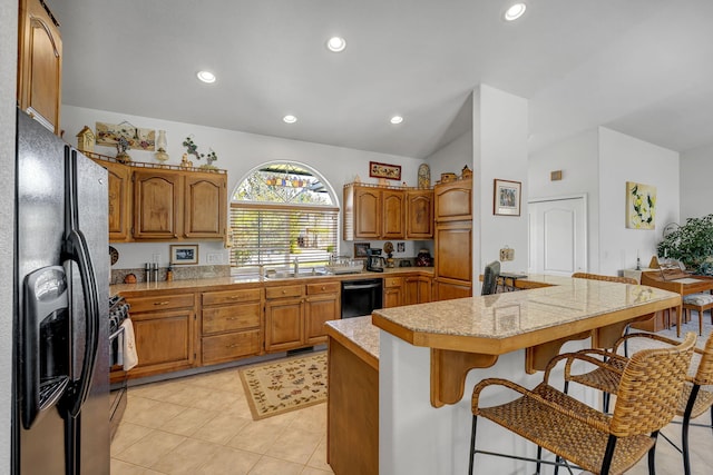 1634 Buzzys Ranch Rd, Carson City, NV 89701 - kitchen featuring black appliances, vaulted ceiling, a kitchen breakfast bar, brown cabinets, and a sink