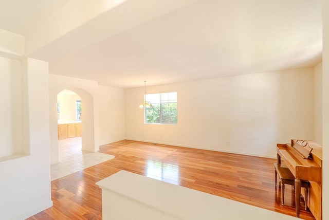 2413 San Remo Dr, Sparks, NV 89434 - spare room featuring arched walkways, a chandelier, light wood finished floors, and baseboards