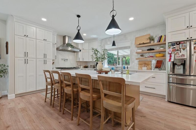 5470 Weatherby Ct, Reno, NV 89523 - kitchen featuring appliances with stainless steel finishes, wall chimney range hood, a sink, light countertops, and light wood-style flooring