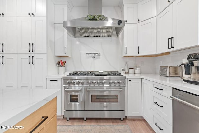 5470 Weatherby Ct, Reno, NV 89523 - kitchen featuring appliances with stainless steel finishes, wall chimney range hood, white cabinetry, light wood-style flooring, and light stone counters