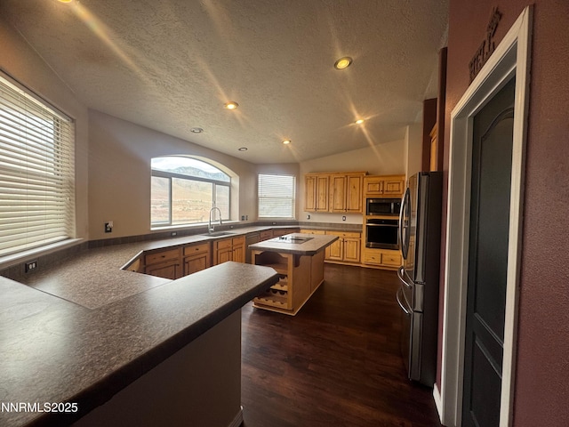 9485 Zaring Ave, Winnemucca, NV 89445 - kitchen featuring appliances with stainless steel finishes, dark wood-type flooring, a kitchen island, a textured ceiling, and dark countertops