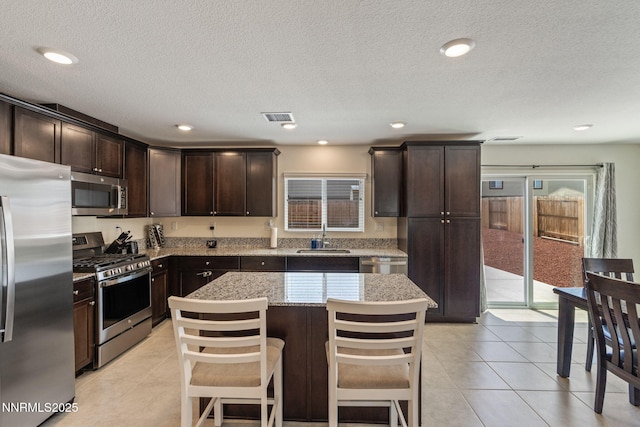 8944 Elk Ravine Dr, Reno, NV 89506 - kitchen with appliances with stainless steel finishes, a sink, dark brown cabinets, light tile patterned floors, and a textured ceiling