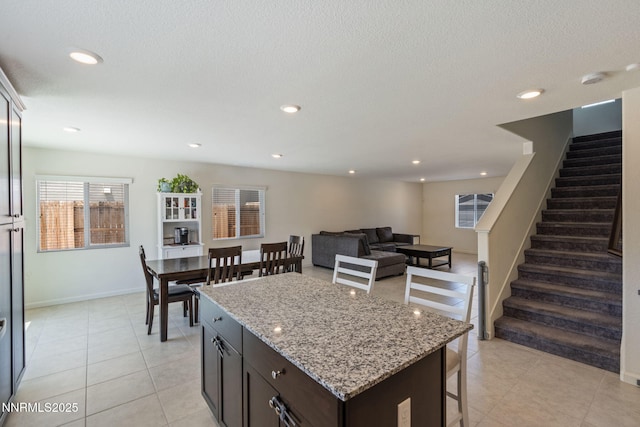 8944 Elk Ravine Dr, Reno, NV 89506 - kitchen with a center island, a breakfast bar area, light tile patterned flooring, light stone counters, and recessed lighting