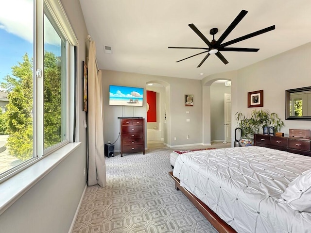 10555 Hampton Creek Dr, Reno, NV 89521 - bedroom featuring baseboards, arched walkways, light colored carpet, ensuite bathroom, and ceiling fan