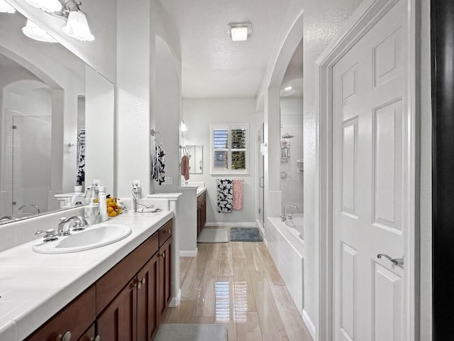 10555 Hampton Creek Dr, Reno, NV 89521 - bathroom featuring a shower stall, a garden tub, a textured ceiling, vanity, and wood finished floors