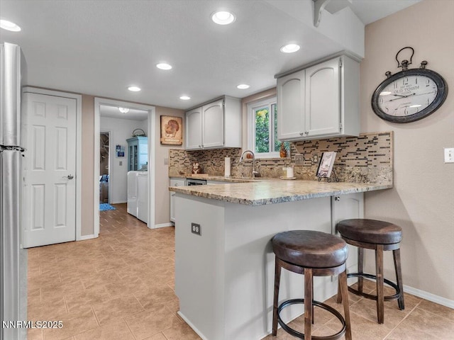 1992 Hackamore Ln, Gardnerville, NV 89410 - kitchen featuring a peninsula, backsplash, a breakfast bar area, baseboards, and a sink