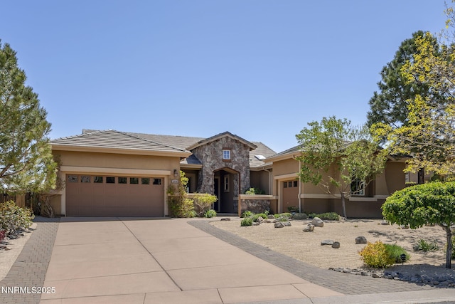 2698 Wind Feather Trl, Reno, NV 89511 - view of front facade with a garage, stone siding, concrete driveway, and stucco siding