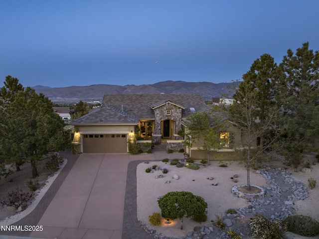 2698 Wind Feather Trl, Reno, NV 89511 - view of front facade featuring stone siding, an attached garage, concrete driveway, stucco siding, and a mountain view
