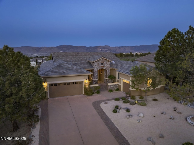 2698 Wind Feather Trl, Reno, NV 89511 - view of front of property with stucco siding, a garage, driveway, a mountain view, and stone siding