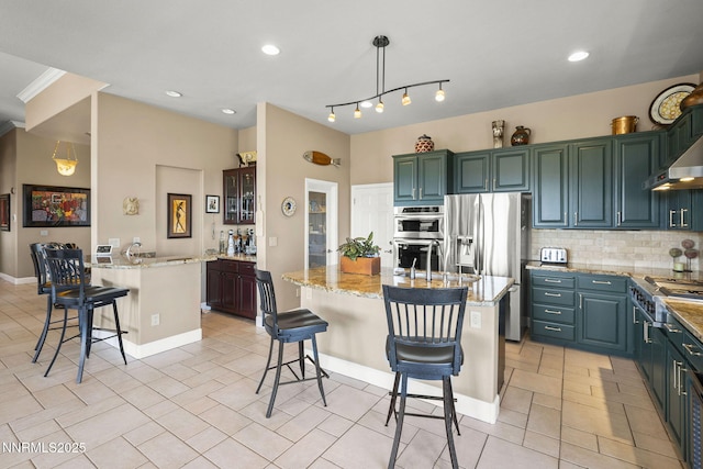 2698 Wind Feather Trl, Reno, NV 89511 - kitchen featuring a kitchen breakfast bar, decorative backsplash, a center island with sink, stainless steel appliances, and light stone counters