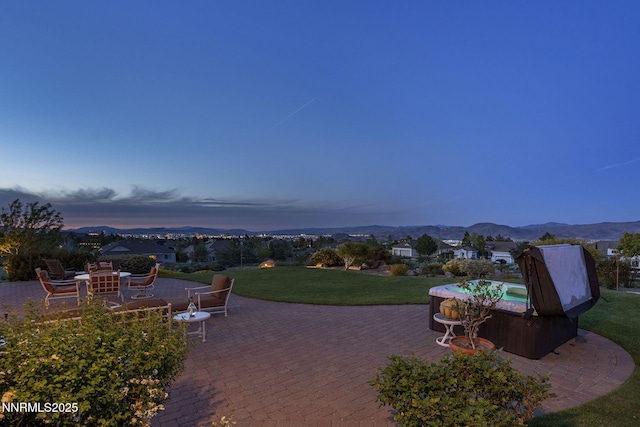 2698 Wind Feather Trl, Reno, NV 89511 - patio terrace at dusk with a hot tub, a patio, a lawn, and a mountain view