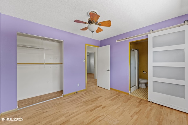 2480 Courtland Way, Sparks, NV 89431 - unfurnished bedroom with wood finished floors, a closet, baseboards, a barn door, and a textured ceiling