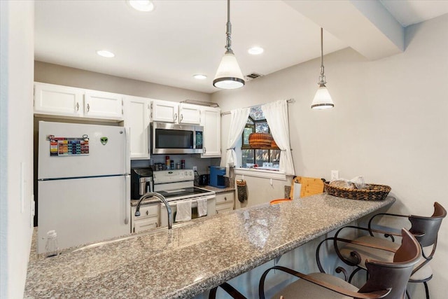 2249 Kietzke Ln Apt C, Reno, NV 89502 - kitchen featuring white appliances, white cabinetry, decorative light fixtures, a kitchen bar, and recessed lighting
