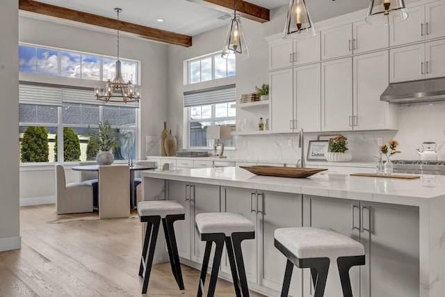 107 Bridlemoor Ct, Reno, NV 89511 - kitchen with under cabinet range hood, a chandelier, beamed ceiling, decorative backsplash, and light wood-style floors