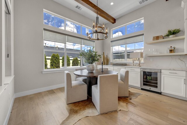 107 Bridlemoor Ct, Reno, NV 89511 - dining room featuring wine cooler, beam ceiling, a chandelier, light wood-style floors, and baseboards