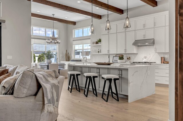 107 Bridlemoor Ct, Reno, NV 89511 - kitchen featuring under cabinet range hood, a chandelier, a center island, decorative backsplash, and beam ceiling