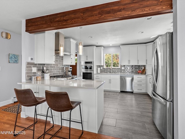 60 Redstone Dr, Reno, NV 89512 - kitchen with stainless steel appliances, a peninsula, decorative backsplash, a breakfast bar area, and wall chimney exhaust hood