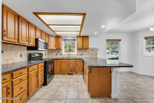 3277 Dartmouth Ct, Carson City, NV 89703 - kitchen with black range with electric cooktop, stainless steel microwave, a peninsula, brown cabinetry, and a breakfast bar