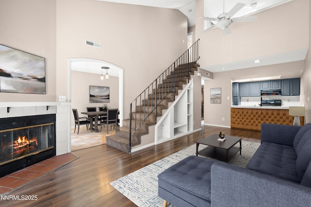 8670 Dixon Ln, Reno, NV 89511 - living room with dark wood-type flooring, a towering ceiling, ceiling fan, stairway, and baseboards