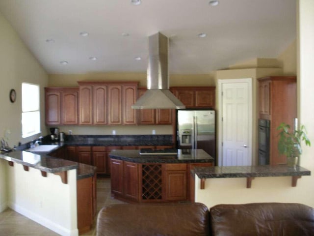 14295 Black Eagle Ct, Reno, NV 89511 - kitchen with stainless steel fridge, a peninsula, island exhaust hood, a kitchen bar, and a sink