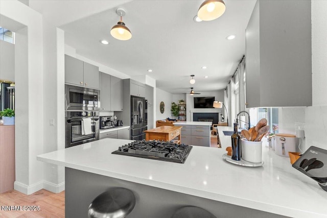 5540 Twin Creeks Dr, Reno, NV 89523 - kitchen featuring black appliances, gray cabinets, a peninsula, a fireplace, and recessed lighting