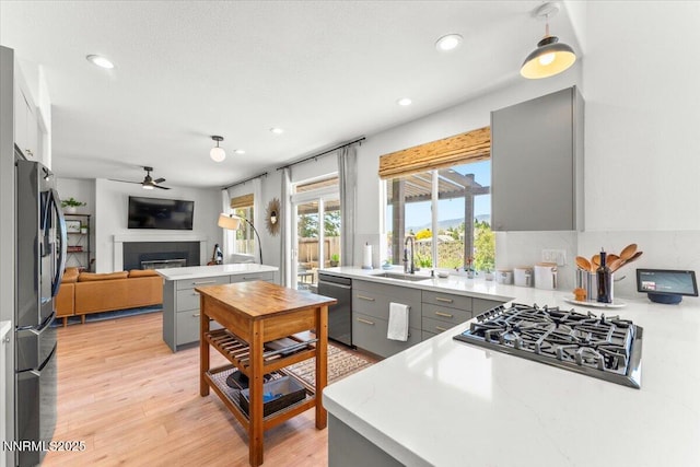 5540 Twin Creeks Dr, Reno, NV 89523 - kitchen with gray cabinetry, appliances with stainless steel finishes, open floor plan, a tile fireplace, and recessed lighting