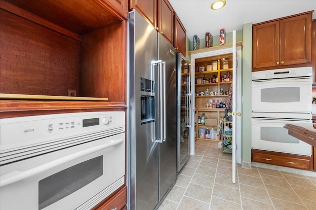 410 Pheasant Dr, Fallon, NV 89406 - kitchen with white double oven, high end fridge, light tile patterned floors, and brown cabinets