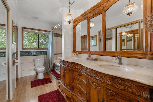 410 Pheasant Dr, Fallon, NV 89406 - bathroom featuring crown molding, toilet, wood finished floors, double vanity, and tile walls